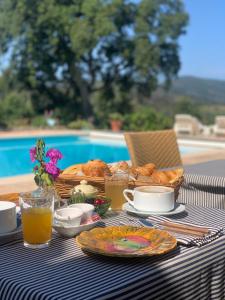 uma mesa com pequeno-almoço de pão e sumo de laranja em Hôtel La Boulangerie em Grimaud