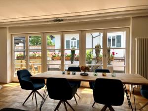 una sala da pranzo con tavolo, sedie e finestre di FeWo Rosenstraße - Exklusive Ferienwohnung im Herzen von Tegernsee a Tegernsee