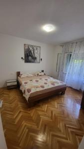 een slaapkamer met een bed en een houten vloer bij Apartmani Matea in Trogir