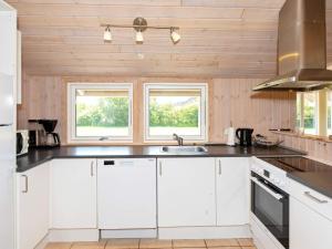 BrovstにあるHoliday Home Kronvildtvej IVの白いキャビネットと2つの窓付きのキッチン