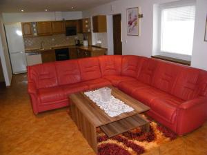 a red leather couch in a living room with a table at Ubytovanie u Grošíka in Oščadnica