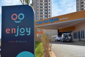 a sign in front of a building with an emyu sign at Apto completo no Enjoy Solar das águas park resort in Olímpia