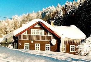 a wooden house with snow on the roof at Chalupa Sněhurka in Polubný