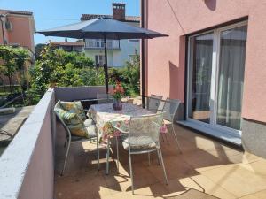 d'une table, de chaises et d'un parasol sur le balcon. dans l'établissement Adel apartment, à Izola