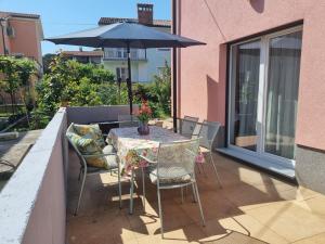 a table and chairs with an umbrella on a balcony at Adel apartment in Izola