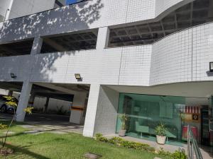 a white brick building with a parking lot at Home Boa Viagem in Recife