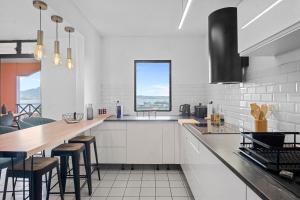 a kitchen with white cabinets and a counter with stools at Duplex standing et confort - Baby ready - 2 minutes de la plage Anse Mitan in Les Trois-Îlets