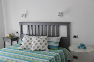 a bedroom with a bed with a striped blanket and pillows at Appartamento Lungomare Toscanelli in Lido di Ostia