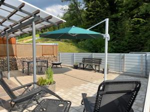 eine Terrasse mit einem Tisch, einem Sonnenschirm und Bänken in der Unterkunft Tiny Haus Dornbirn in Dornbirn