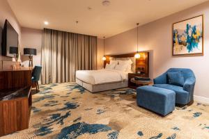 une chambre d'hôtel avec un lit et une chaise bleue dans l'établissement فندق رويال دايموند الطائف, à Taif