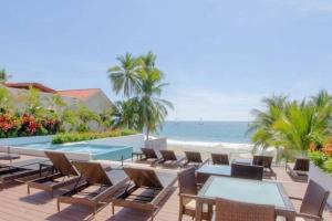 a resort with a pool and chairs and the ocean at Beautiful beach front apartment in Ixtapa. in Ixtapa
