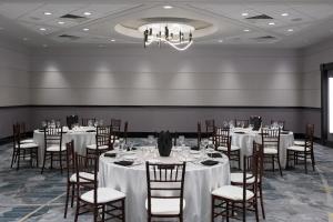uma sala de banquetes com mesas e cadeiras e um lustre em Marriott Chicago O’Hare em Rosemont