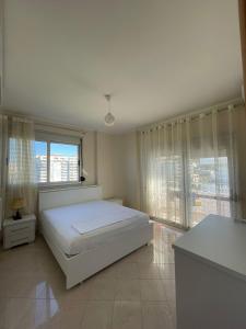 a bedroom with a white bed and a large window at ANISA Vlore in Vlorë