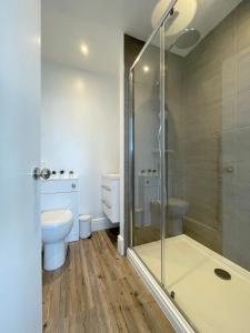 a bathroom with a toilet and a glass shower at Môr Heli Guest House Criccieth in Criccieth