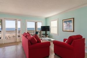 ein Wohnzimmer mit 2 roten Stühlen und Meerblick in der Unterkunft The Seaclusion Top Floor - 300 Seventh Street in Saint Simons
