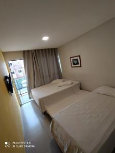 two beds in a hotel room with a window at Manawa Beach Flats Prime in Porto De Galinhas