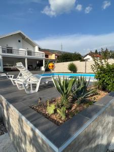 a patio with two white chairs and a swimming pool at Villa Zak in Blagaj