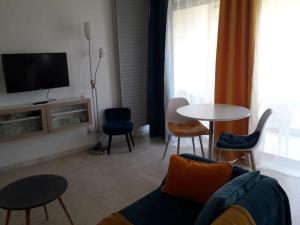 ein Wohnzimmer mit einem Sofa, Stühlen und einem Tisch in der Unterkunft Appartement paisible, résidence avec piscine in Mandelieu-la-Napoule