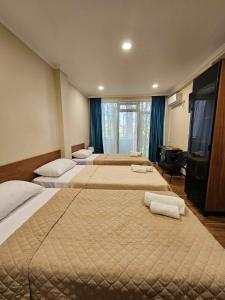 a hotel room with three beds with towels on them at Villa Story Hotel in Shekhvetili