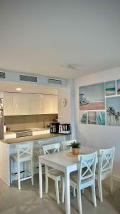 a kitchen with a white table and chairs and a counter at Rincón Idilia (Málaga). in Rincón de la Victoria