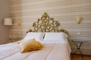 ein Schlafzimmer mit einem weißen Bett mit einem goldenen Kopfteil in der Unterkunft Amalpha Domus Apartment in Amalfi