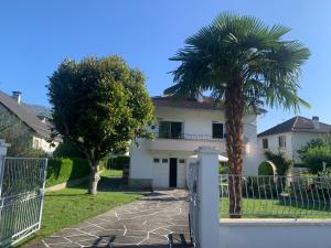 a white house with a palm tree and a fence at Villa de charme jardin vue sur montagnes rénovation 2026 in Argelès-Gazost