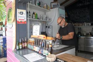 un homme debout à un comptoir dans un bar avec des bouteilles dans l'établissement Vacances à la plage, à Sainte-Anne