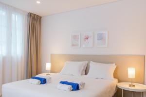 a bedroom with a large white bed with towels on it at Downtown PDL Premium in Ponta Delgada