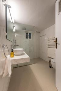 a bathroom with a sink and a mirror and a toilet at Coastal Getaway: Roomy Beachside Apartment! in Nea Makri +13 photos