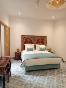 a bedroom with a large bed and a chandelier at Riad Mellah in Essaouira