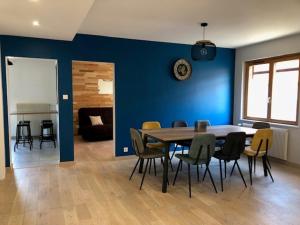 ein Esszimmer mit einer blauen Wand sowie einem Tisch und Stühlen in der Unterkunft Les trois pierres in Eguisheim