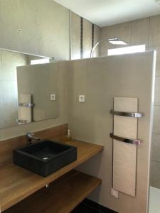 een badkamer met een zwarte wastafel en een spiegel bij Les trois pierres in Eguisheim