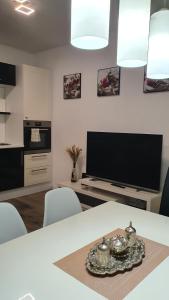 ein Wohnzimmer mit einem Tisch und einem TV in der Unterkunft Apartmani Gandi in Bihać