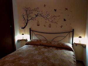 een slaapkamer met een bed met vogels en een boom aan de muur bij La Casa in Piazza in Toffia