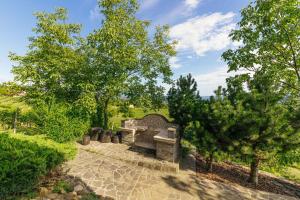 a stone bench in a garden with trees at Cosy Hill Home Rucman With a Breathtaking View in Zgornja Pohanca