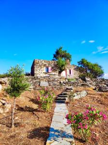 ein Steinhaus auf einem Hügel mit rosa Blumen in der Unterkunft OWL’S NEST/THE PINK COTTAGE in Ioulis