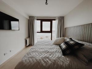 a bedroom with a large bed with a large window at Aunaisin - Amundsen I in Ushuaia