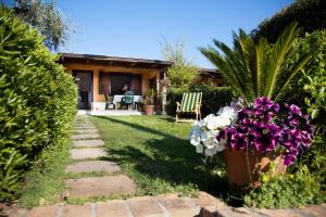 a garden with purple and white flowers and a house at Alloggio incantevole con piscina in Ricadi