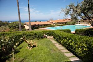 a yard with a pool and a chair in the grass at Alloggio incantevole con piscina in Ricadi