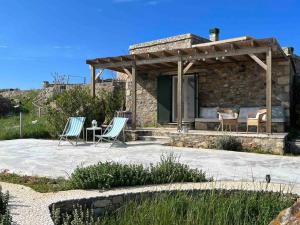 ein Steinhaus mit 2 Stühlen und einem Tisch in der Unterkunft Bozcaada / Tenedos Ayana ve Midilli panoraması in Canakkale