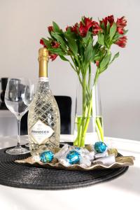a bottle of wine and a vase with red flowers at Silver SPA - 22 in Dziwnów