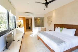 a bedroom with a large bed and a television at Casa Imox Luxe Studio in Tulum