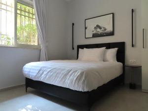 um quarto com uma cama com lençóis brancos e uma janela em White Moon Inn em Jerusalém