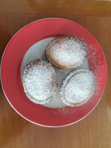 three donuts in a red bowl on a table at Astra in Agerola
