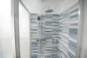 y baño con ducha y azulejos azules y blancos. en Glicine Apartment, en Costermano
