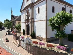 un bâtiment avec des fleurs sur le côté d'une rue dans l'établissement Gite Paon, à Kintzheim