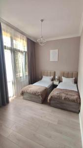 um quarto com 2 camas e uma grande janela em Guest House NIMA em Kutaisi