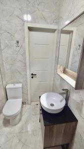 La salle de bains est pourvue de toilettes, d'un lavabo et d'un miroir. dans l'établissement Guest House NIMA, à Koutaïssi