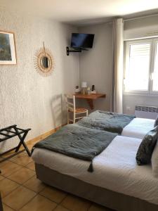 a bedroom with two beds and a table and a television at Hôtel Restaurant Le Clos Charmant in Vallon-Pont-dʼArc