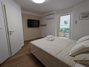 a bedroom with a bed and a tv and a window at Olea Rooms Piran Old Town in Piran